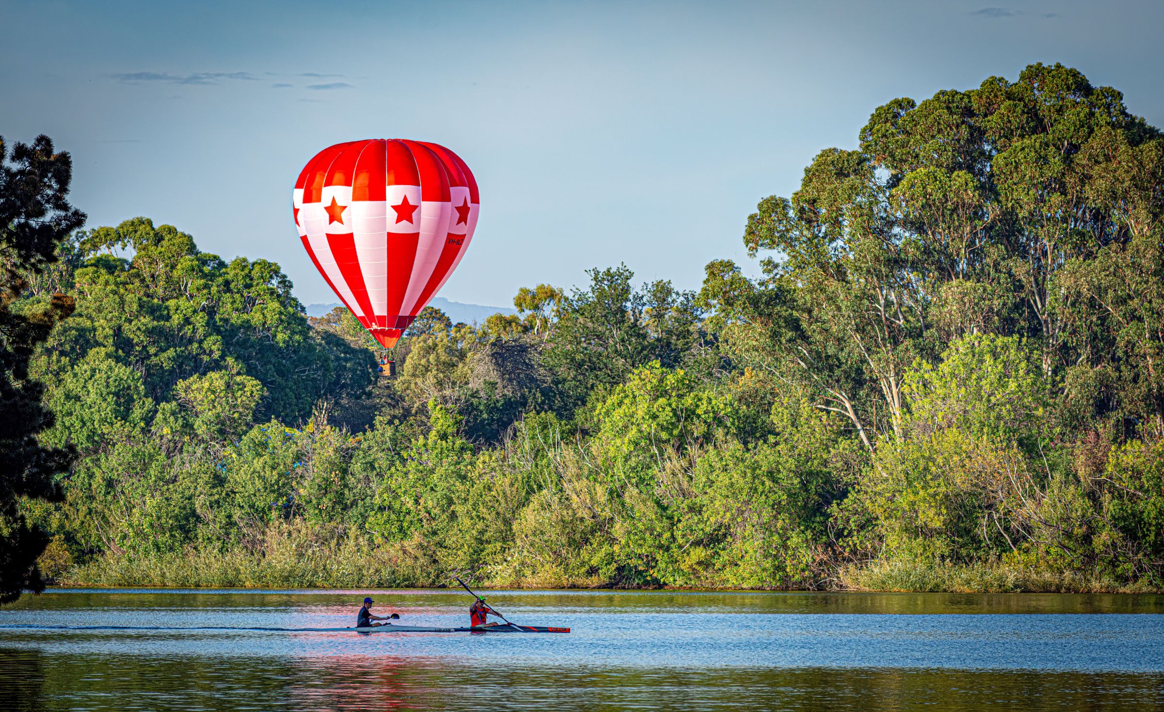 Canoeists on Lake Burley Griffin beneath a red hot-air balloon